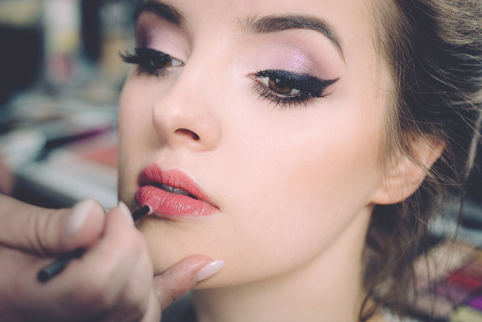 Penata rias memoles lipstik pada wajah model